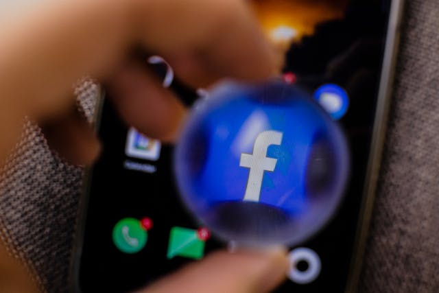 The Facebook mobile app icon viewed through a magnifying lens. 