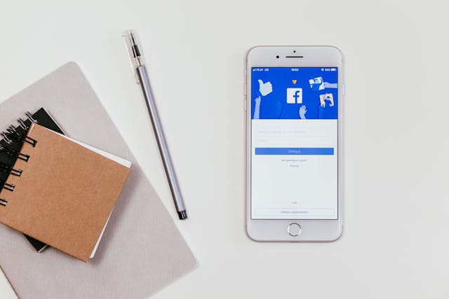 A notepad and smartphone, with Facebook open on the screen. 