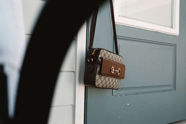 A Gucci handbag hanging from a doorknob. 