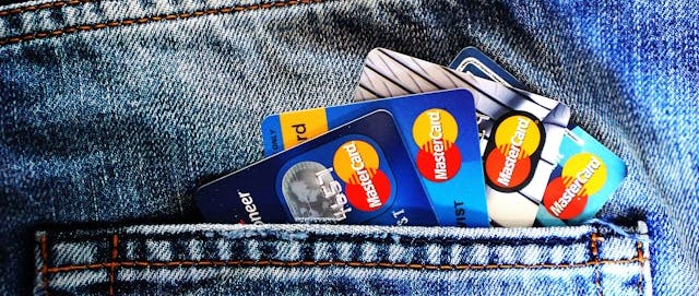 Several Mastercard cards tucked into the back pocket of some jeans.