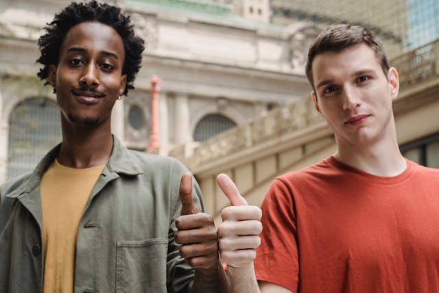 Two men giving a thumbs up sign. 