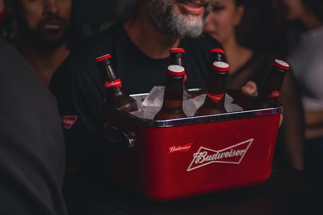 A man carrying a crate of Budweiser bottles. 
