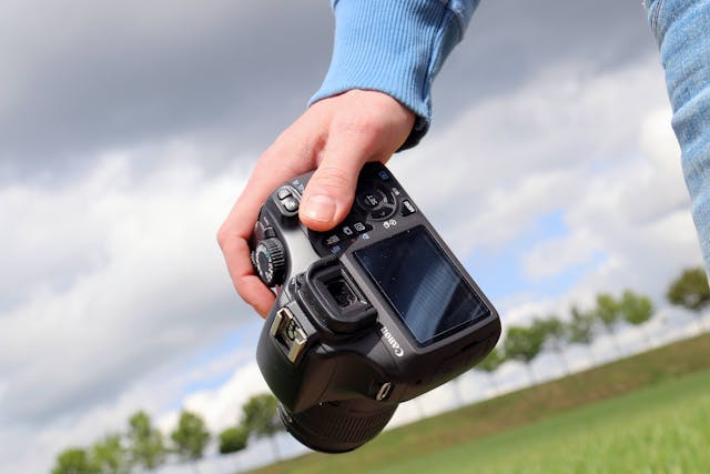 A hand holding a Canon DSLR camera. 