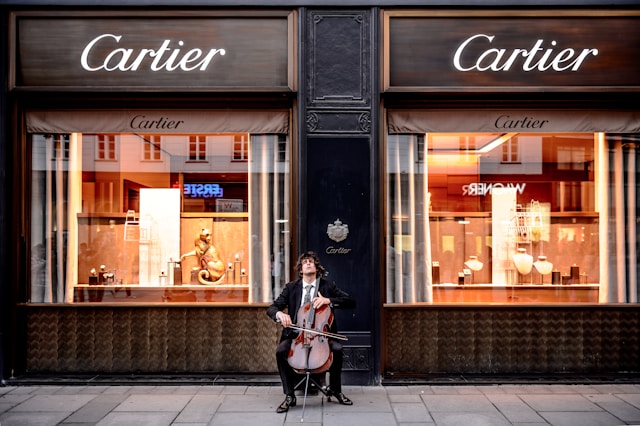 A man playing cello outside a Cartier store.