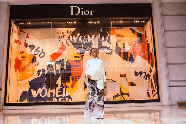 A woman standing in front of a Dior store window. 