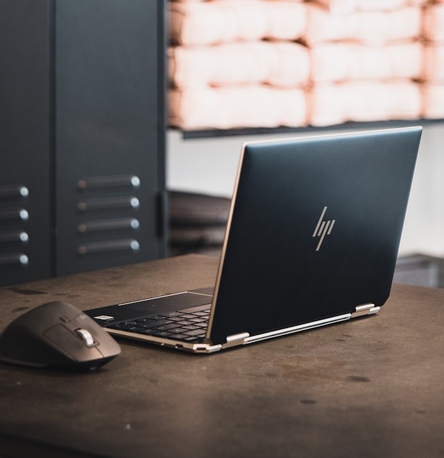 HP laptop and mouse on a desk. 