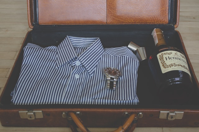 A bottle of Hennessy packed in a suitcase along with a smart shirt and watch. 