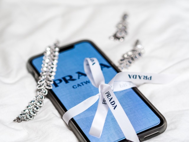 Prada jewelry resting on a smartphone. 