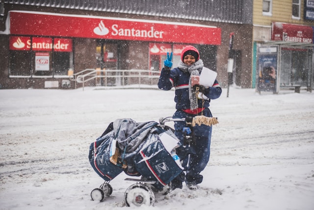 A mail delivery worker outside a Santander bank branch in the snow.