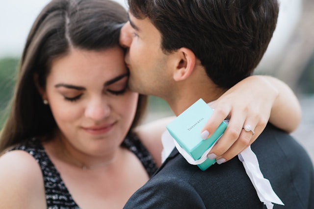 A woman holding a Tiffany gift box as she embraces a man. 