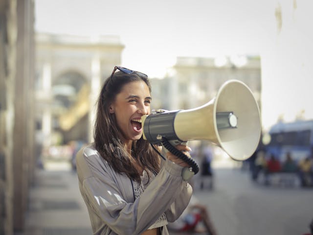 A business woman shouting into a loudhailer. 