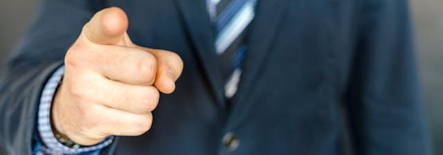 A businessman pointing his finger at his camera.