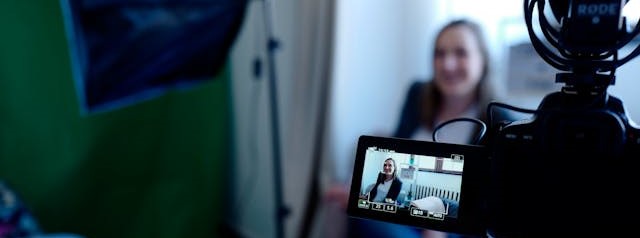 A business woman talking in front of a video camera.