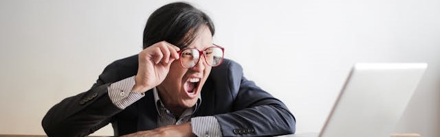 A business man yelling in frustration at his laptop.