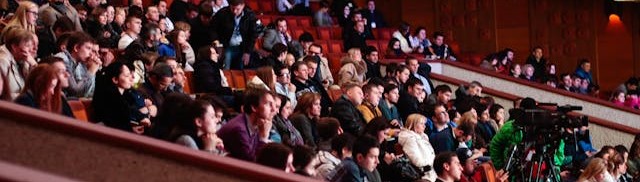 An audience at an event in and auditorium.