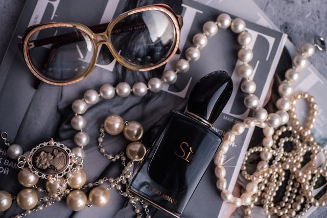 Armani perfume, sunglasses and jewellery sitting on a fashion magazine. 