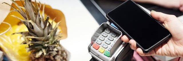 A customer paying for goods with a smartphone on a contactless reader.