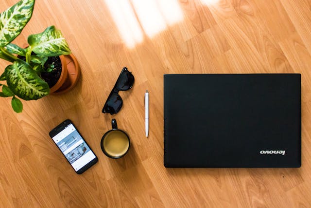 Lenovo laptop and smartphone on a table with a cup of coffee.