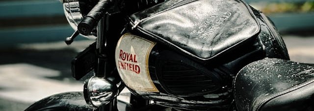 A close-up of the Royal Enfield logo on the fuel tank of a Meteor 650 motorcycle.